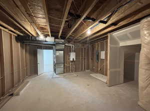 Basement with heating unit, electric panel, and tankless water heater