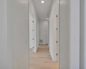 Hallway with baseboards, light wood-style flooring, visible vents, and recessed lighting