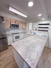 Kitchen with stainless steel appliances, kitchen peninsula, sink, and light wood-type flooring