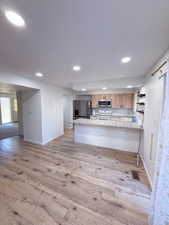 Kitchen with stainless steel appliances, sink, light hardwood / wood-style floors, and kitchen peninsula