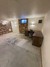 Office area featuring a paneled ceiling, concrete flooring, and brick wall