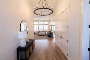 Corridor featuring hardwood / wood-style flooring, a chandelier, and a high ceiling