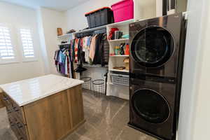 Laundry room in Primary Bathroom featuring stacked washer and clothes dryer and dark carpet