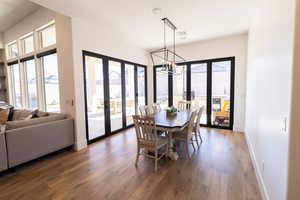 Dining space with a notable chandelier, dark wood-type flooring, french doors, and a healthy amount of sunlight