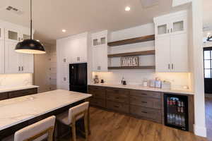 Kitchen featuring white cabinetry, beverage cooler, and decorative light fixtures