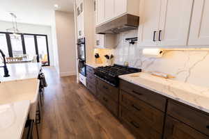 Kitchen featuring pendant lighting, stainless steel appliances, custom range hood, and white cabinets