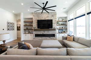 Living room with plenty of natural light, hardwood / wood-style floors, a stone fireplace, and built in shelves