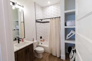 Full bathroom with shower / tub combo with curtain, vanity, wood-type flooring, and toilet