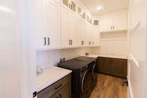 Laundry room with cabinets, separate washer and dryer, and light hardwood / wood-style flooring