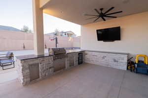 View of patio featuring exterior kitchen, area for grilling, and ceiling fan and tv