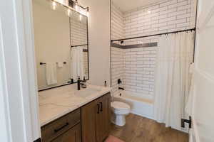 Full bathroom featuring shower / tub combo, hardwood / wood-style floors, vanity, and toilet