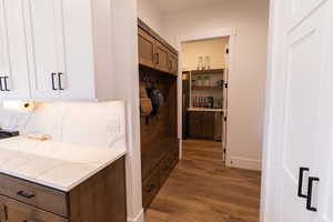 Kitchen with light stone counters, backsplash, dark hardwood / wood-style floors, and white cabinets