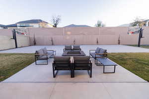 View of patio with an outdoor living space and basketball hoop and firepit