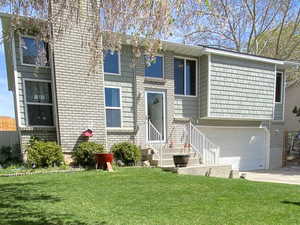 Back of property featuring fence, concrete driveway, a lawn, and an attached garage