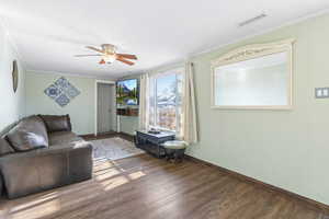 Living room with hardwood / wood-style flooring, crown molding, and ceiling fan