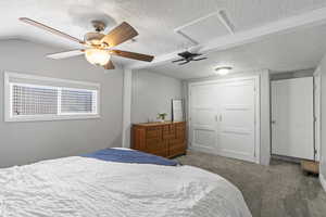 Carpeted bedroom with ceiling fan, a closet, and a textured ceiling