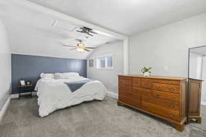 Bedroom with lofted ceiling, ceiling fan, a textured ceiling, and carpet