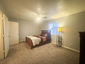 Carpeted bedroom with ceiling fan and a textured ceiling