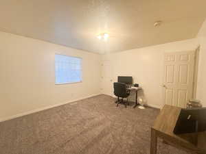 Carpeted home office featuring a textured ceiling