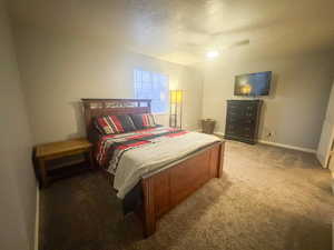 Bedroom featuring ceiling fan, a textured ceiling, and carpet