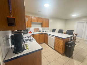 Kitchen with sink, light tile patterned floors, kitchen peninsula, white appliances, and range hood