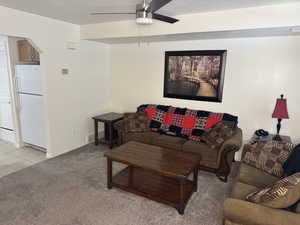 Living room with ceiling fan and light carpet