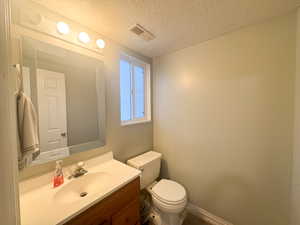 Bathroom with vanity, a textured ceiling, and toilet