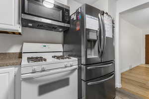 Kitchen with white cabinetry, stainless steel appliances, and light hardwood / wood-style floors