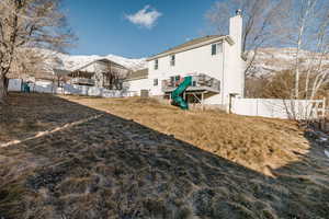 Massive, fully fenced backyard with a playground and slide off of deck.