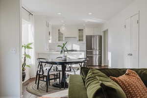 Kitchen featuring tasteful backsplash, hardwood / wood-style floors, white cabinets, and stainless steel refrigerator