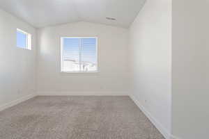 Primary. Carpeted empty room with vaulted ceiling and great amount of natural light.