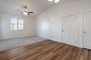 Unfurnished room featuring vaulted ceiling, light wood-style flooring, and ceiling fan.