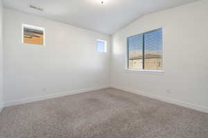 Primary. Carpeted empty room with vaulted ceiling and great amount of natural light.