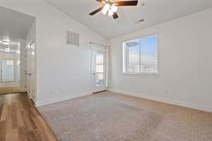 Unfurnished room with wood-style flooring, vaulted ceilings, and ceiling fan.