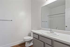 Bathroom featuring grey vanity, wood-style floors, shower/bathtub combination, and toilet.