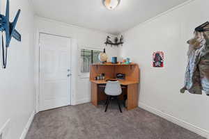 Home office with ornamental molding and carpet flooring