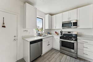 Kitchen with white cabinetry, appliances with stainless steel finishes, sink, and a textured ceiling