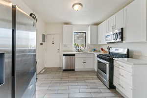 Kitchen featuring white cabinetry, sink, a textured ceiling, and appliances with stainless steel finishes