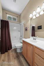 Full bathroom with shower / tub combo with curtain, vanity, hardwood / wood-style flooring, and toilet