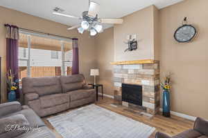 Living room featuring light hardwood / wood-style flooring, a fireplace, and ceiling fan