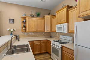 Kitchen featuring tasteful backsplash, sink, white appliances, light hardwood / wood-style floors, and a textured ceiling