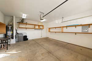 Garage featuring a garage door opener, electric panel, and water heater