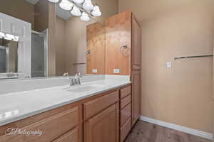 Bathroom with vanity, hardwood / wood-style floors, an enclosed shower, and an inviting chandelier