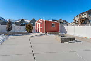 Snow covered patio with a storage shed and a fire pit