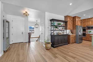 Kitchen with hanging light fixtures, stainless steel appliances, light hardwood / wood-style floors, and a chandelier