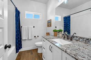 Full bathroom featuring wood-type flooring, toilet, vanity, and plenty of natural light