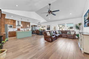 Living room featuring sink, high vaulted ceiling, ceiling fan, and light wood-type flooring