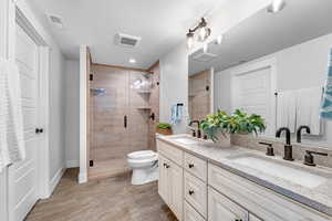 Bathroom featuring an enclosed shower, vanity, and toilet