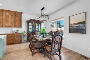 Dining space with light hardwood / wood-style flooring and a chandelier