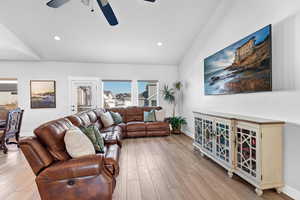 Living room with vaulted ceiling, ceiling fan, and light hardwood / wood-style floors